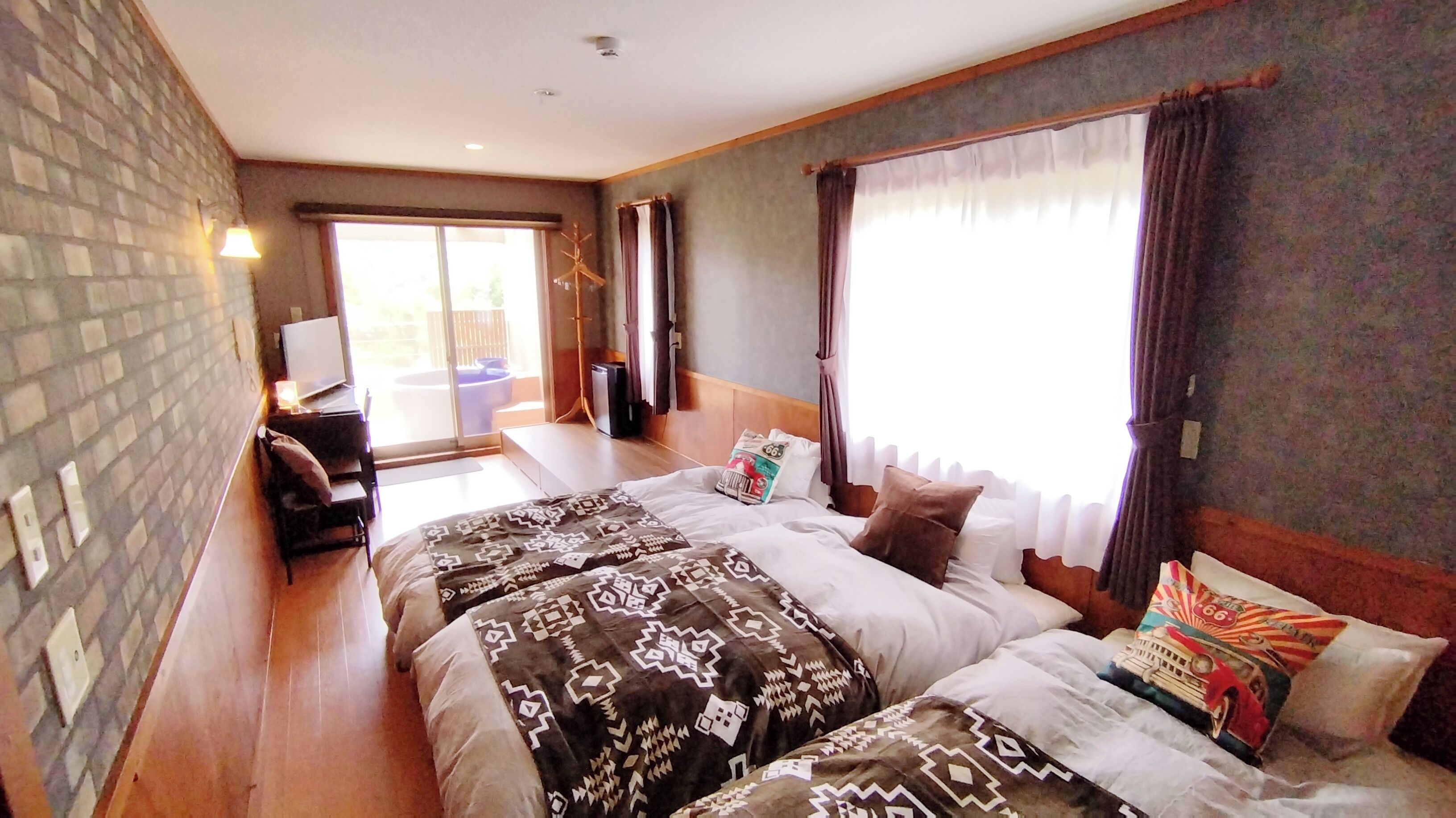 Habitación de hotel con dos camas, televisión, escritorio y balcón.