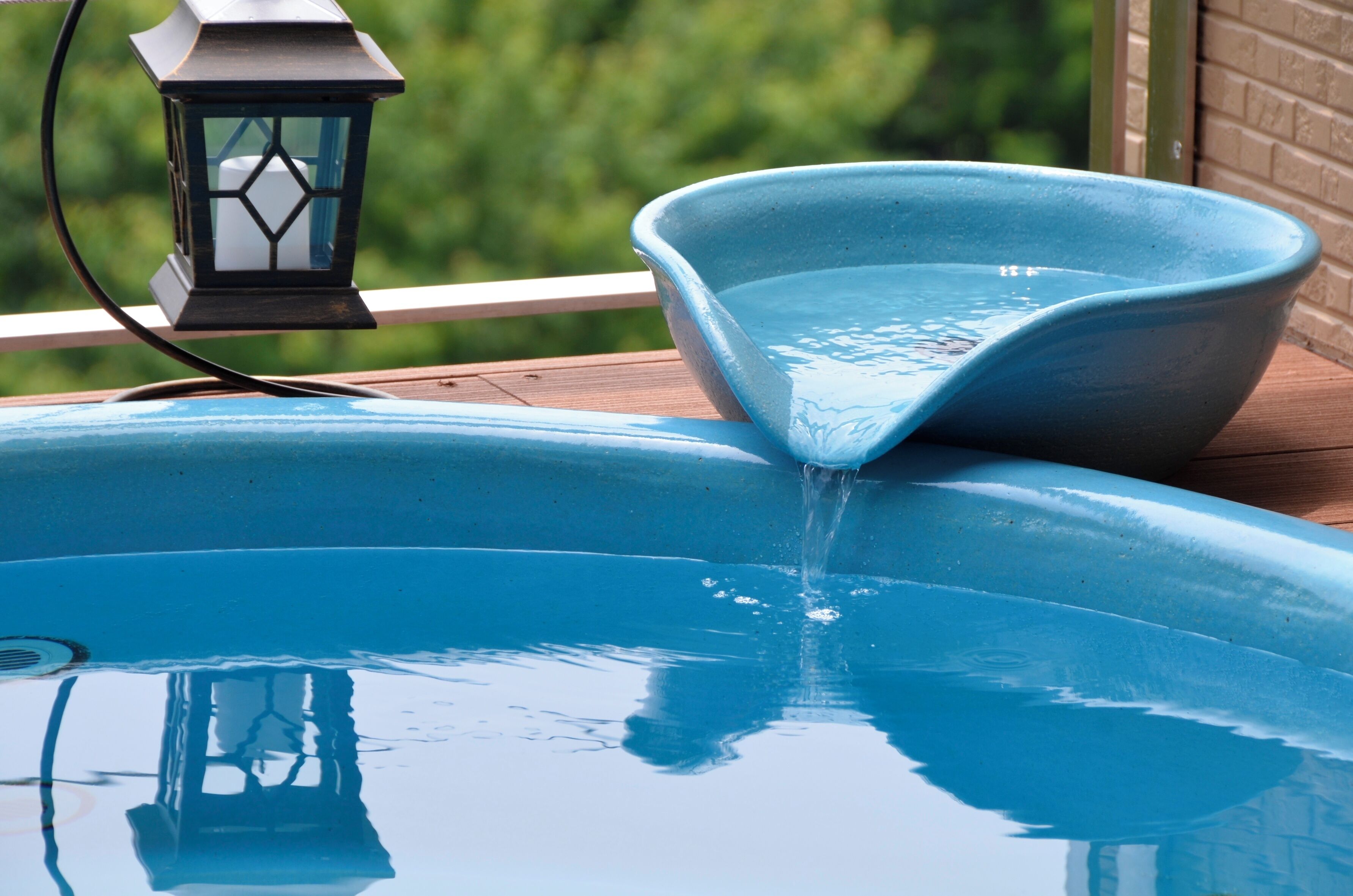 A swimming pool with a blue bowl-shaped edge, a lantern, and a wooden deck.