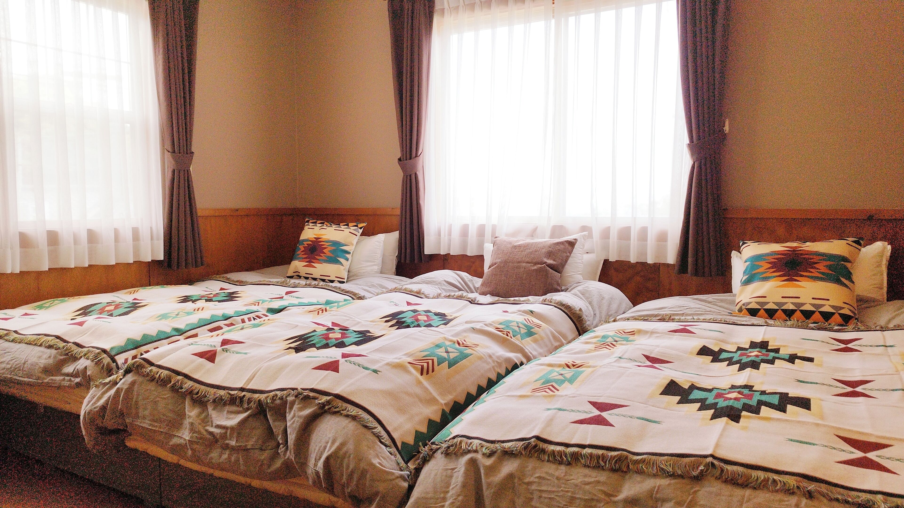 A hotel room with two beds, each with a patterned bedspread and pillows.