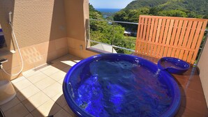 A hot tub on a balcony with a view of a forested hillside and the ocean. - kokopellihouseizukogen (Ito)