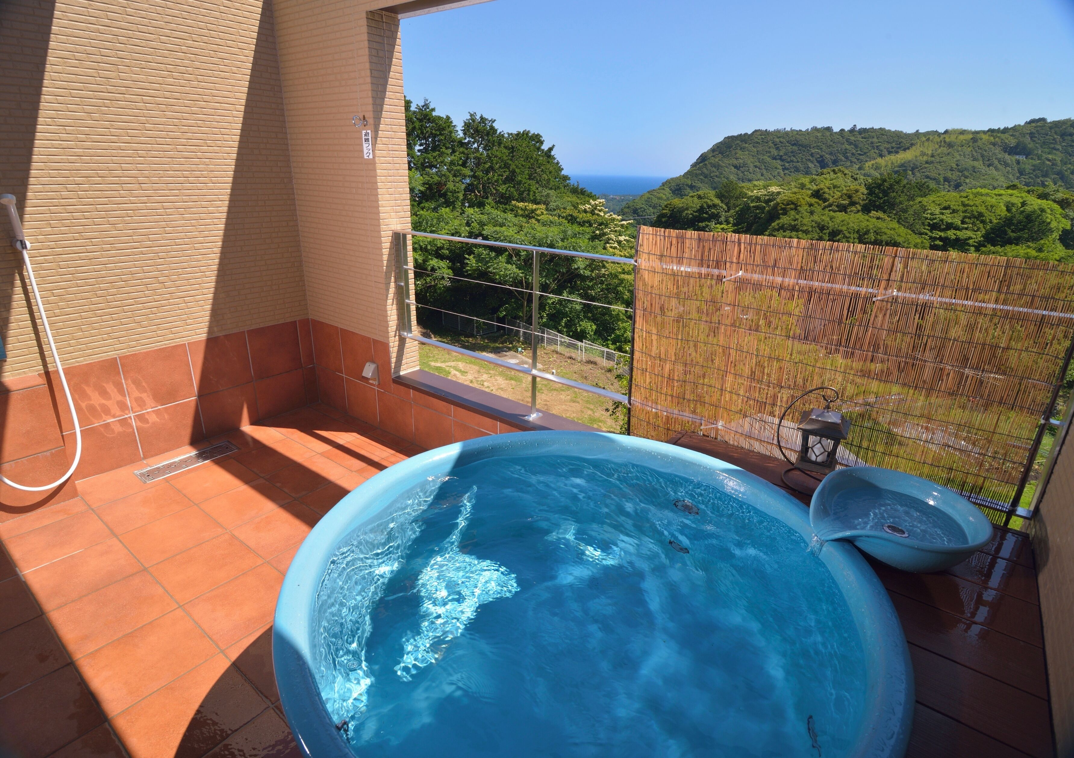 A hot tub on a balcony with a view of a lush green landscape and the sea.