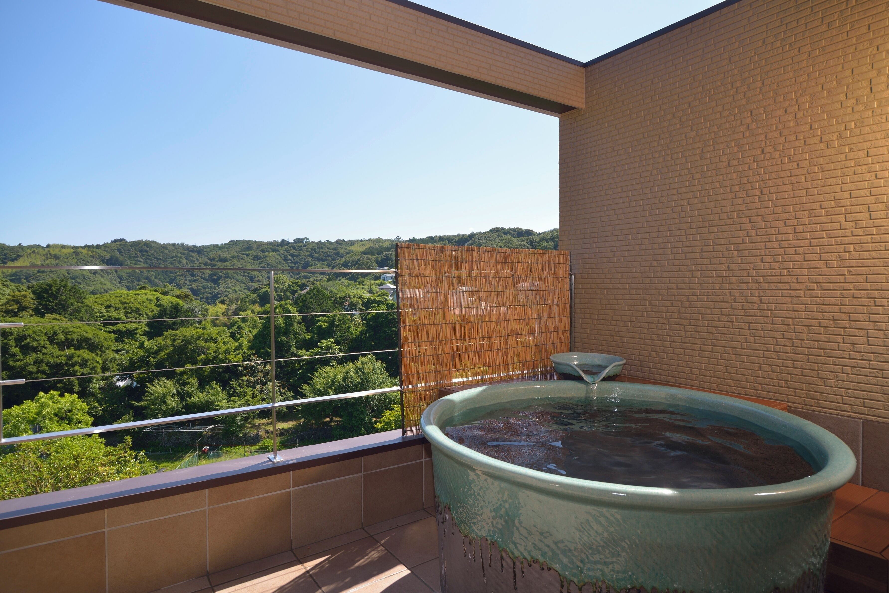 Un jacuzzi en un balcón con vista a un paisaje verde.