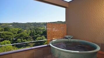 Un jacuzzi en un balcón con vista a un paisaje verde.