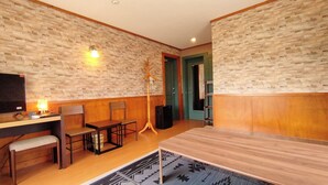 A room with a wooden desk, two chairs, a television, a speaker, and a patterned rug. - kokopellihouseizukogen (Ito)