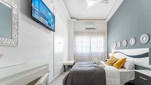 Un dormitorio moderno con cama, mesita de noche y televisor montado en la pared.