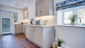 Eine moderne Küche mit weißen Schränken, einer eingebauten Mikrowelle und einem Fenster mit Blick ins Freie.