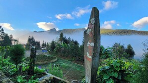A serene lakeside view with a wooden post in the foreground, surrounded by lush greenery and a clear sky. - Homestay Khám Phá Y Tý (Y Ty)