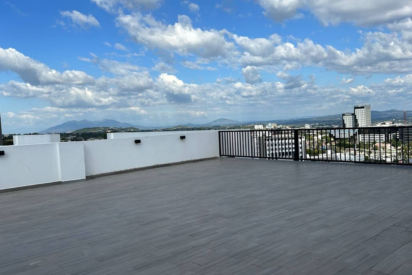 A rooftop terrace with a view of a cityscape and mountains.