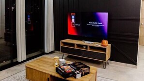 A modern living room with a flat-screen TV, wooden coffee table, and a patterned rug.