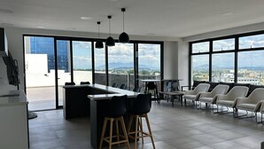 A modern kitchen with a bar area, large windows, and a view of the city.