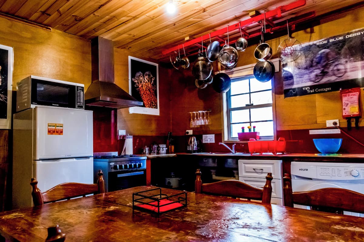 Eine Küche mit Holzausstattung, einem Kühlschrank, Herd und hängenden Töpfen.