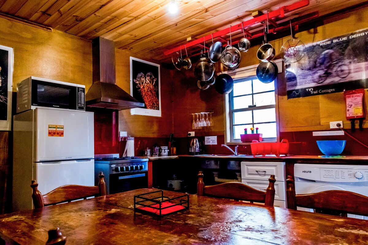 Eine Küche mit Holzausstattung, einem Kühlschrank, Herd und hängenden Töpfen.