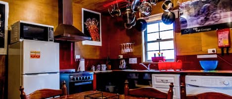 Une cuisine avec des meubles de rangement en bois, un réfrigérateur, une cuisinière et des casseroles suspendues.