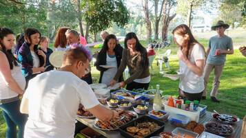 A group of people gathered around a buffet table with various food items and condiments.