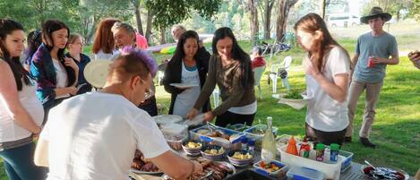 A group of people gathered around a buffet table with various food items and condiments.