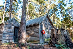 Une cabane en bois avec une porte en métal et une boîte aux lettres rouge.