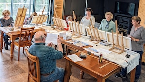 Un groupe de personnes participait à un cours d’art, des chevalets et du matériel de peinture étant disposés sur des tables.