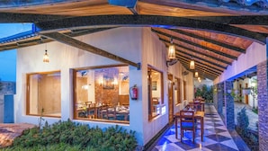 A modern building with large windows, a covered patio area, and a stone-tiled entrance. - Quinta Premium Resort, Corbett (Kaladhungi)