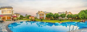 A swimming pool with a tiled edge, surrounded by a well-maintained lawn and trees.