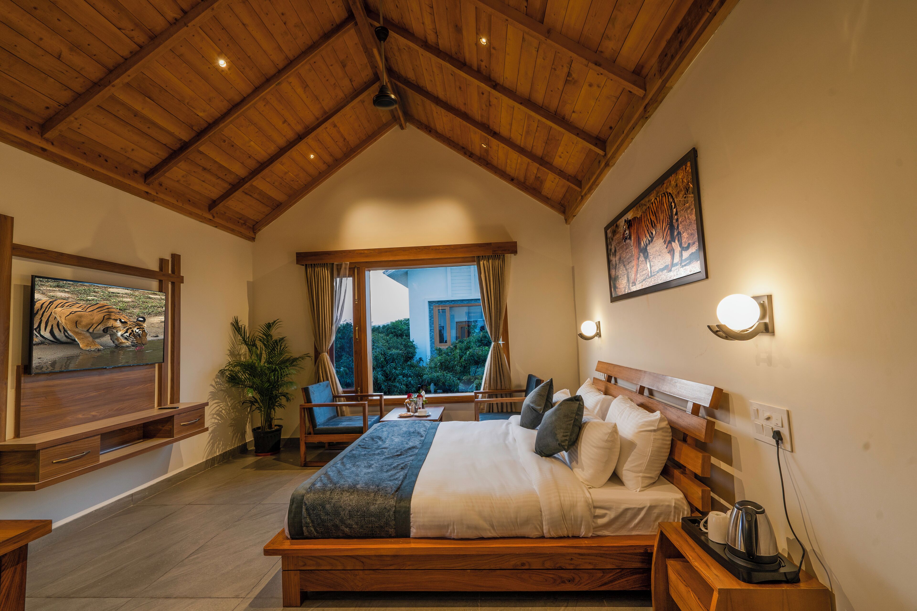 A bedroom with a wooden ceiling, a bed with pillows, a nightstand, a TV, and a window with curtains.