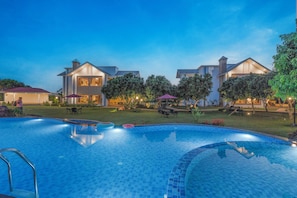 A swimming pool with a tiled edge, surrounded by a well-maintained lawn and trees.