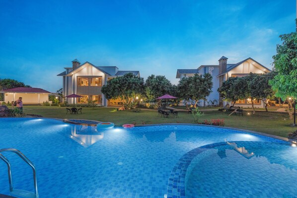 A swimming pool with a tiled edge, surrounded by a well-maintained lawn and trees.