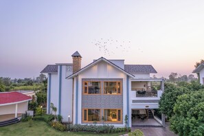 A modern two-story house with a balcony, a chimney, and a well-maintained garden. - Quinta Premium Resort, Corbett (Kaladhungi)