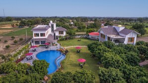 A residential property with a swimming pool, multiple houses, and a well-maintained lawn. - Quinta Premium Resort, Corbett (Kaladhungi)