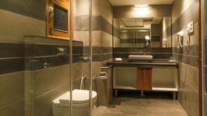 A modern bathroom with a glass-enclosed shower, a toilet, a sink, and a mirror. - Quinta Premium Resort, Corbett (Kaladhungi)