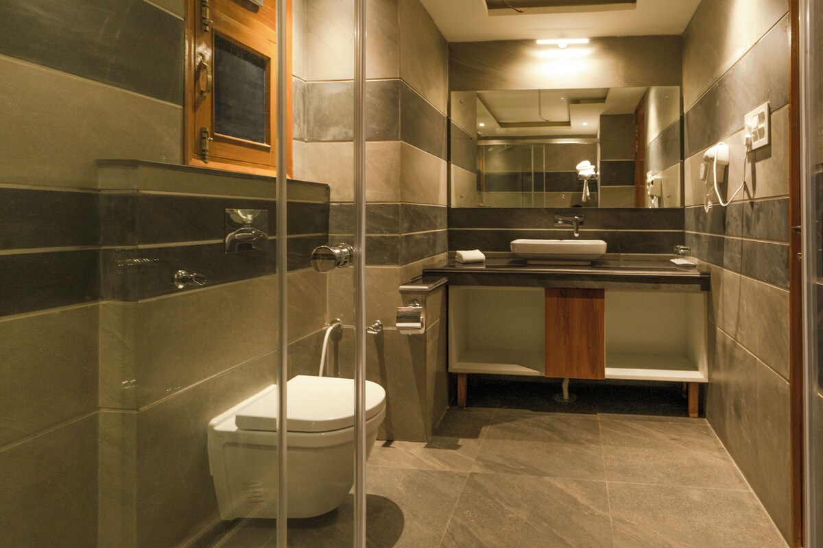 A modern bathroom with a glass-enclosed shower, a toilet, a sink, and a mirror.