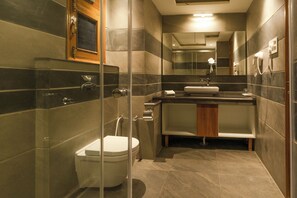 A modern bathroom with a glass-enclosed shower, a toilet, a sink, and a mirror.