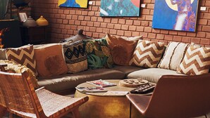 A cozy living room with a brick wall, a sectional sofa, and a round coffee table. - Hôtel Boma (Dakar)