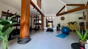 A spacious room with a ceiling fan, exercise equipment, and a large window. - Hôtel Boma (Dakar)