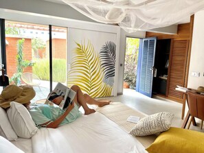A room with a bed, a reading area, and a view of the outside. - Hôtel Boma (Dakar)