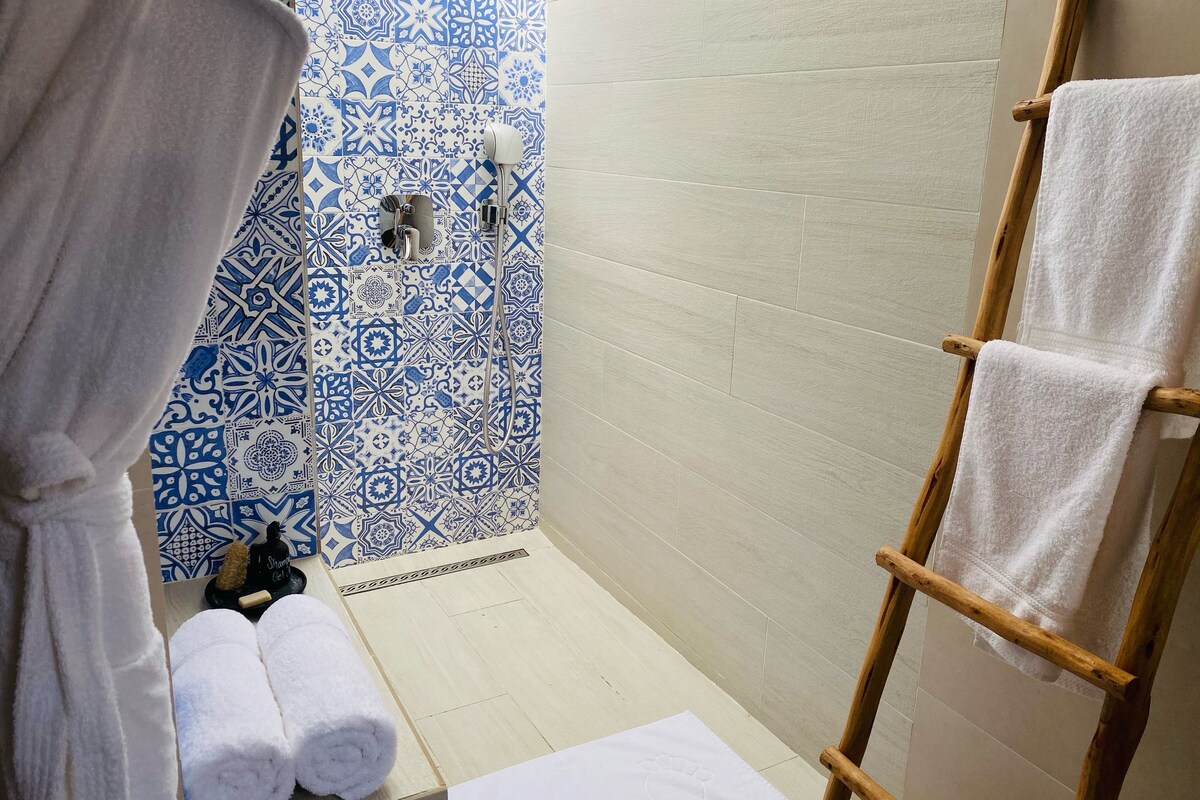 A bathroom with a shower, a wooden ladder, and a patterned wall.