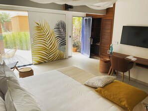 A bedroom with a bed, a desk, a TV, and a sliding glass door leading to a balcony. - Hôtel Boma (Dakar)