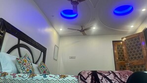 A bedroom with a bed, a ceiling fan, and two blue ceiling lights. - Al Mubeen (Srinagar)