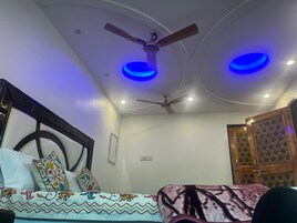 Un dormitorio con una cama, un ventilador de techo y dos luces azules en el techo.