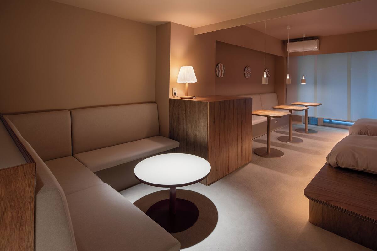 A modern hotel room with a sofa, a round table, a small desk, and a bed.