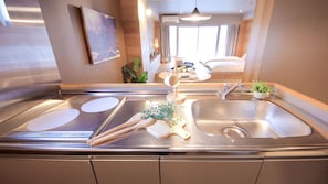 A modern kitchen with a stainless steel sink, a built-in stove, and a small potted plant on the counter. - SEVENSTORIES (Nagoya)