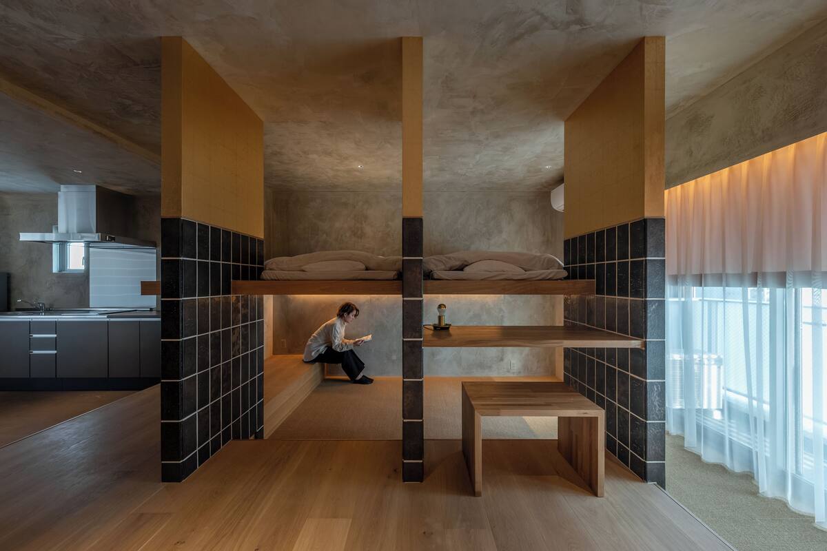 A compact, modern room with a bunk bed, a small desk, and a kitchen area.