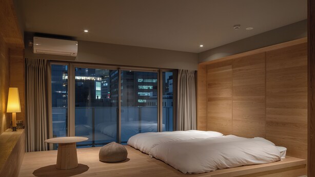 Une chambre à coucher moderne avec un lit, une table de chevet et une vue sur la ville la nuit.