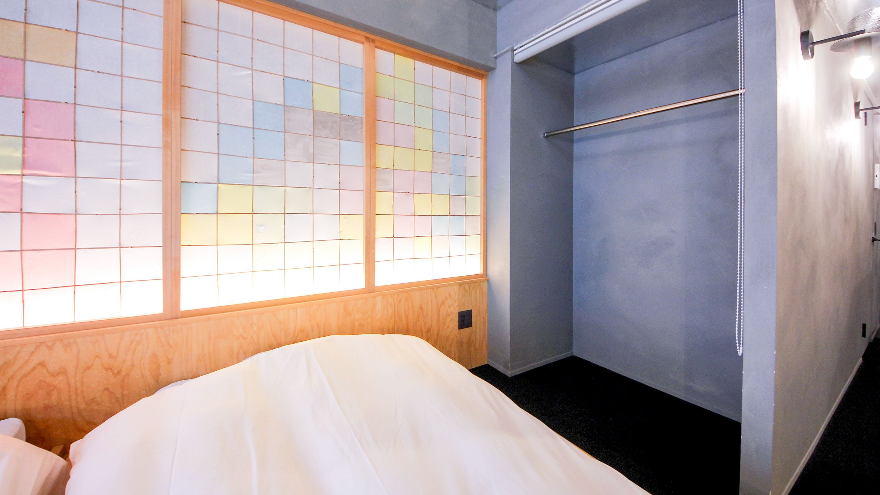 Una habitación de hotel con una cama, un armario y un ventanal con diseño de cuadrícula.
