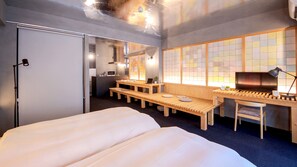 A hotel room with a bed, a desk, a chair, a window with a view, and a kitchenette. - SEVENSTORIES (Nagoya)