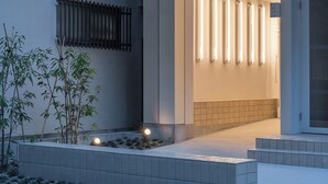 Un bâtiment moderne doté d’un toit plat, d’un balcon et d’une entrée bien éclairée.