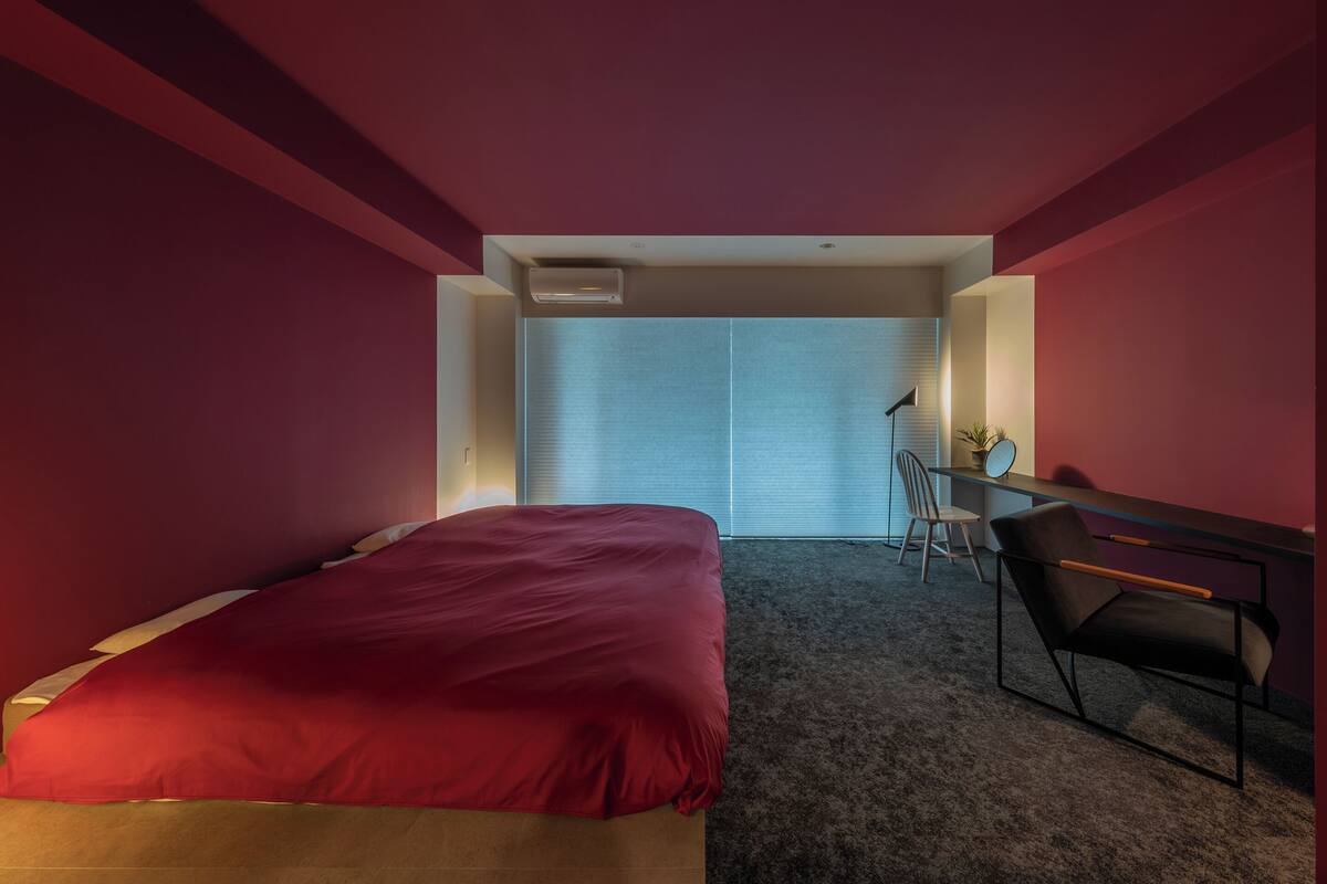 A bedroom with a bed, a desk, and a chair.