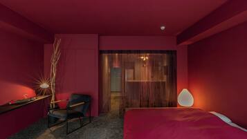 Un dormitorio moderno con temática roja, que incluye una cama, un escritorio, una silla y una lámpara.