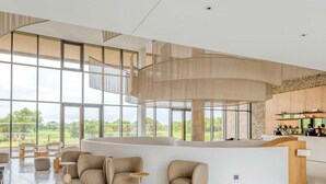 Un vestíbulo espacioso con un mostrador de recepción curvo, asientos cómodos y grandes ventanales con vistas al exterior.