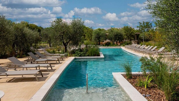 A pool area with lounge chairs and a clear sky.