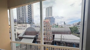 A view from a balcony with a cityscape in the background, including modern high-rise buildings and a traditional temple structure. - NamasStay Silom (Bangkok)